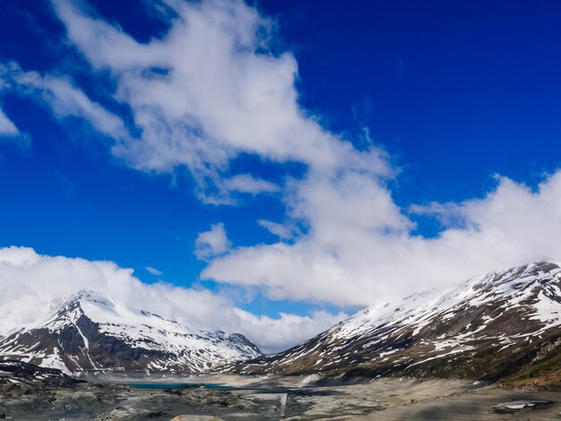 Snow covered rocky landscape against blue sky and clouds