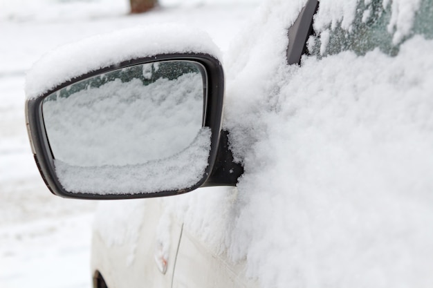 Snow covered side mirror of car closeup