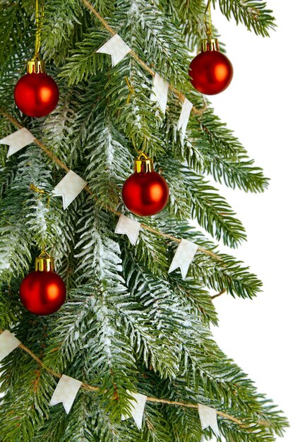 Snow-covered spruce branch with red balls and garland with flags. Christmas frame