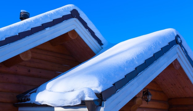 Photo snow drift on roof after of snowfalls on sunny day. wooden house in the snow.