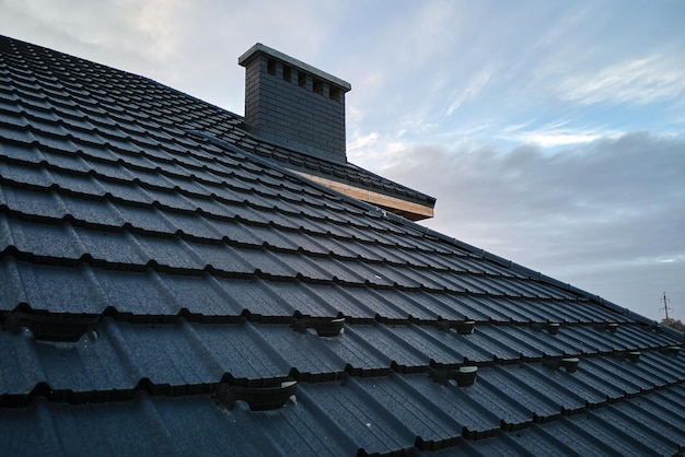 Snow guard for safety in winter on house roof top covered with ceramic shingles. Tiled covering of building.