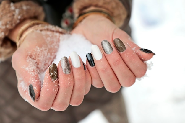 Snow in the hands of a girl with a manicure