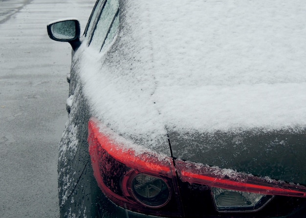 濡れたアスファルト上の車の後部の雪と氷