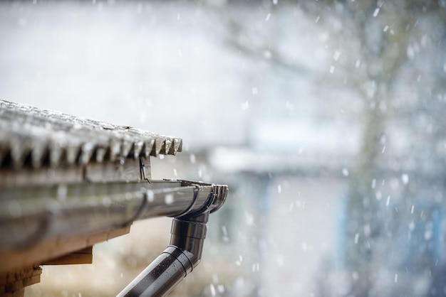 Snow is falling over the roof of the house a cold spring and the return of frosts