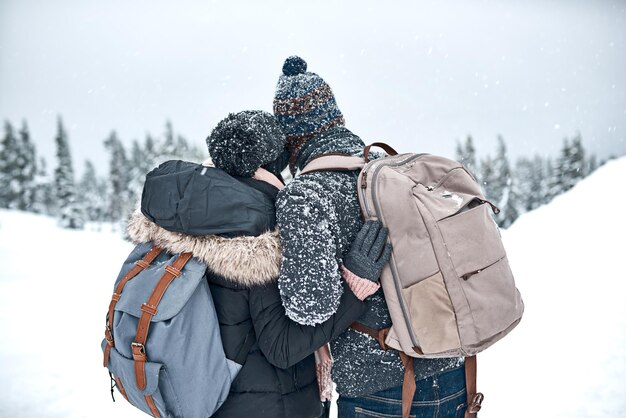 The snow makes everything look beautiful Rearview shot of a couple admiring the snowy view