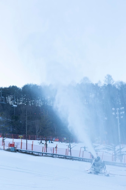 Macchina per la produzione di neve che lavora nella scena della stazione sciistica vuota durante il blocco