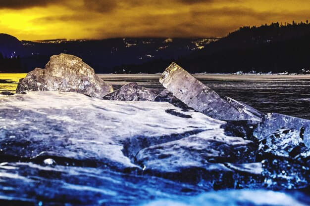 Snow on shore against sky during winter