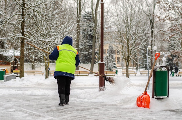 Snow storm in the city Roads and sidewalks covered with snow Worker shovel clears snow Bad winter weather Street cleaning after snowstorm