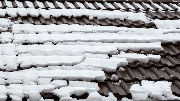 Snow thaws on the tiles of a roof.