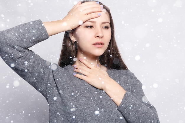 雪、冬、クリスマス、病気、ヘルスケア、人々、薬の概念-喉の痛み。喉の痛みを伴う病気の女性のクローズアップ気分が悪い、美しい少女が雪の背景に手で首に触れる