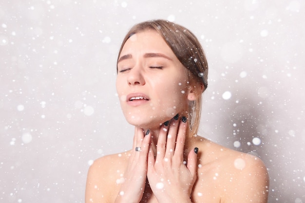 Snow, winter, christmas, Illness, Health Care, people, Medicine concept - Throat Pain. Closeup Of Sick Woman With Sore Throat Feeling Bad. Beautiful Girl Touching Neck With Hand over snow background