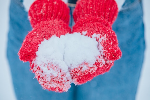 Snow in woman hands in red gloves