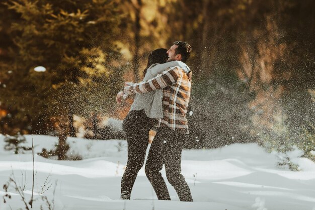 Snowball fight Winter couple having fun playig in snow outdoors Young joyful happy lovers Selective focus