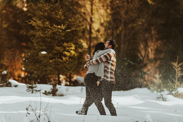 Snowball fight Winter couple having fun playig in snow outdoors Young joyful happy lovers Selective focus