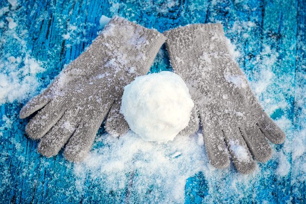 Snowball and mittens on a snowy blue table surface