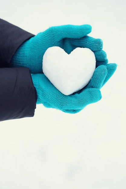 Palla di neve a forma di cuore nelle mani