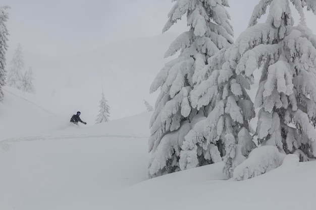 Snowboard freerider moving in deep snow powder downhill on a\
steep slope in the mountains freeride winter sports outdoor