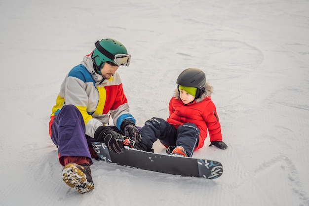 Foto l'istruttore di snowboard insegna a un ragazzo allo snowboard attività per bambini in inverno sport invernali per bambini stile di vita