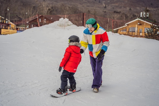 Snowboard instructor teaches a boy to snowboarding Activities for children in winter Children's winter sport Lifestyle