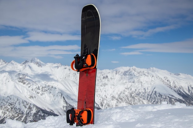 Snowboard stands in the snow at the top of a mountains