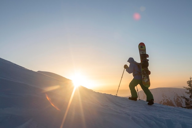 A snowboarder climbs to the top in the rays of the morning sun