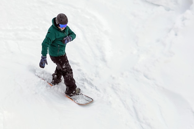 Сноубордист в снаряжении спускается по склону горы