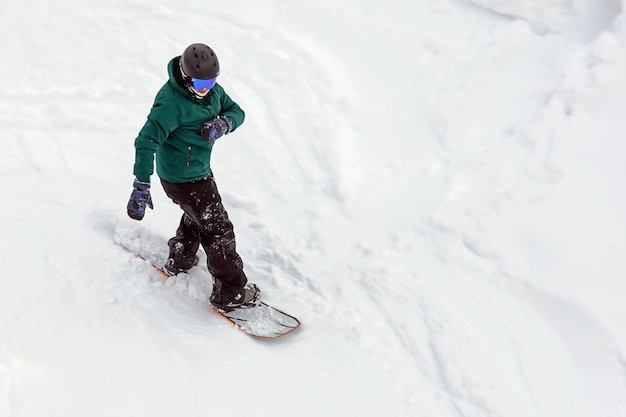 Snowboarder in equipment descends mountain slope