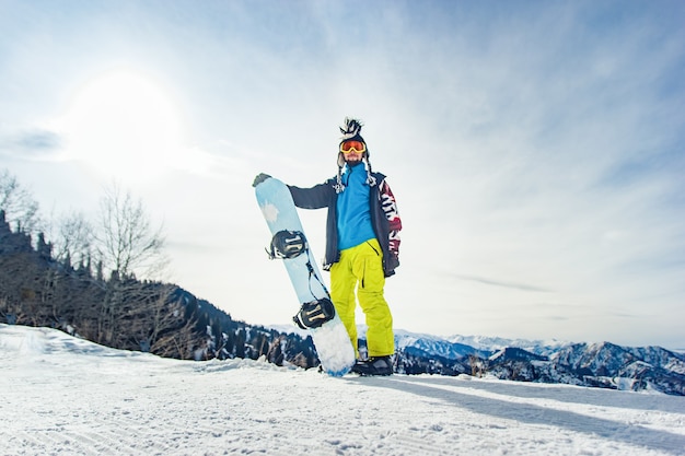 Snowboarder freerider in de bergen bereidt zich voor om af te dalen op de achtergrond van besneeuwde bergen