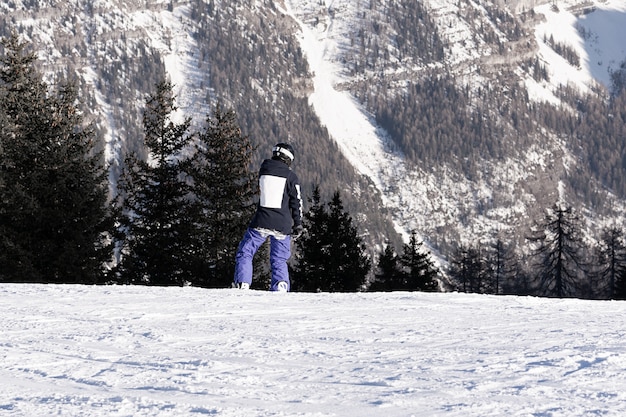 Snowboarder in paarse broek met een snelheid langs de helling tegen van de bergen. Concept mensen, sport