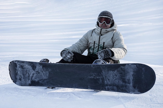 A snowboarder is sitting on top of a mountain The concept of winter sports snowboarding and downhill skiing Holidays in ski resorts