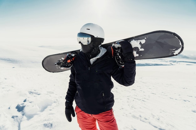 Foto snowboarder met een plank op een besneeuwde berg klaar voor een adrenaline-gevulde afdaling in de winter