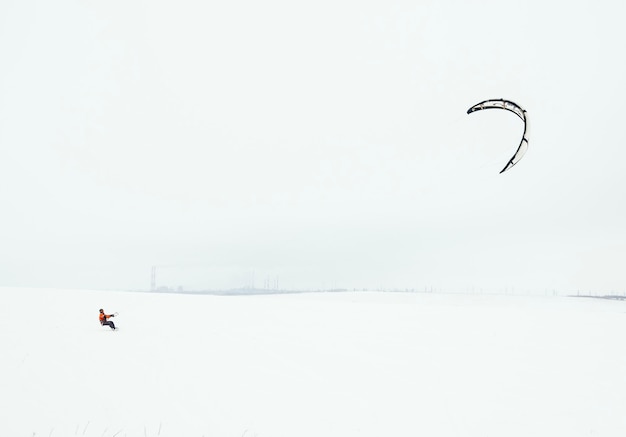 Snowboarder riding a kite on a background of an industrial enterprise