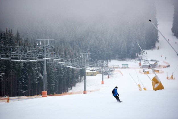 Snowboarder rushing down on ski slope at ski resort