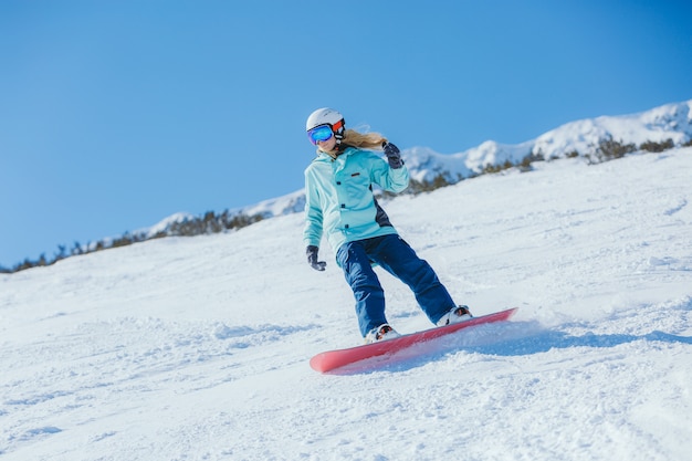 Foto snowboarder sulle piste in una mattina soleggiata. ragazza in abiti da snowboard.