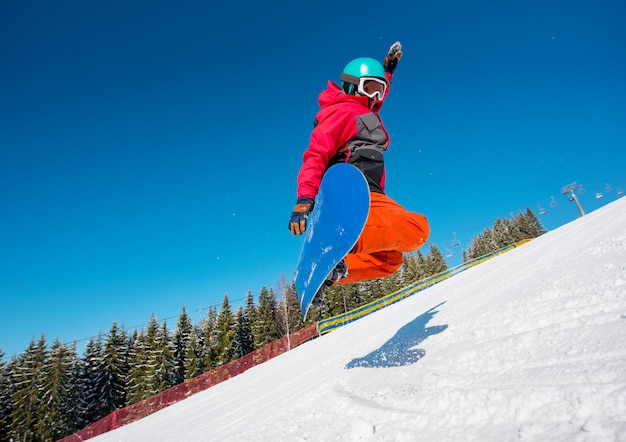 Snowboarder springen in de lucht tijdens het rijden op de helling in de bergen