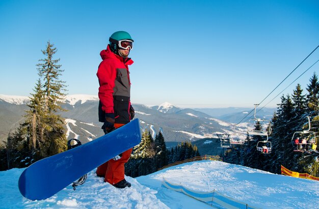 Snowboarder on top of slope in winter evening