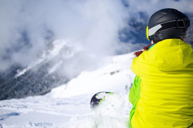 Snowboarder zittend met bergketen op de achtergrond