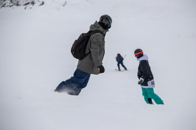 Snowboarders rides down the side of the mountain