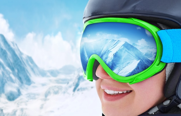 Snowboarding. portrait of young snowboarder girl at the ski resort.Mountain Range Reflected in the Ski Mask