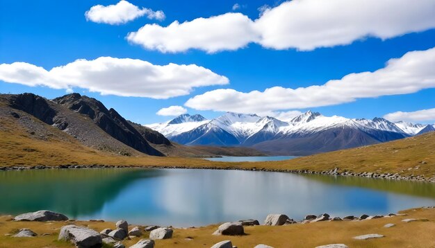 Photo snowcapped mountain peaks behind a rocky hill with sparse green vegetation