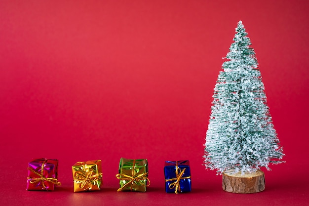 Snowcovered Christmas tree and bright multicolored boxes with gifts