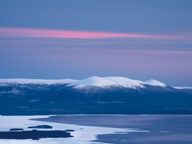 Snowcovered polar cone hills in winter early in the morning Winter polaris landscape View of the snowcovered hills and White sea Cold winter weather Harsh northern climate background