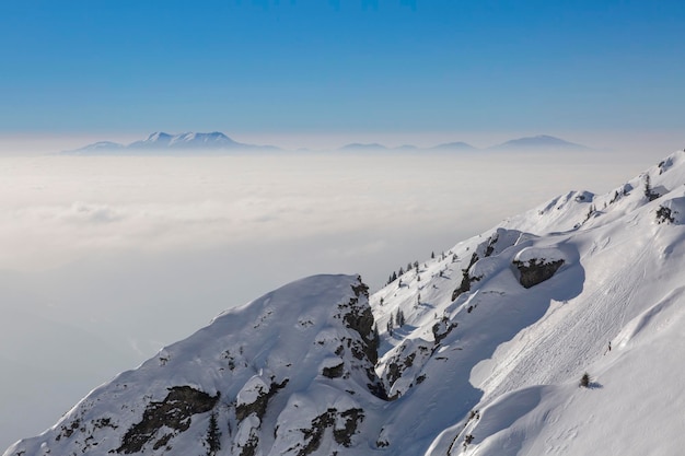 Snowcovered rocks and a mountain range above the clouds