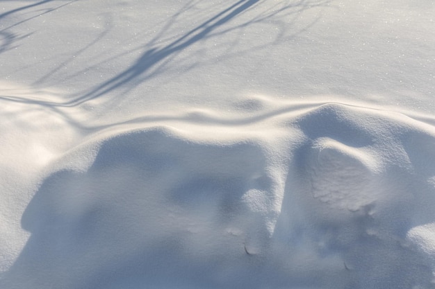 A snowdrift on the surface of the ground in the garden. Natural snow pattern and texture