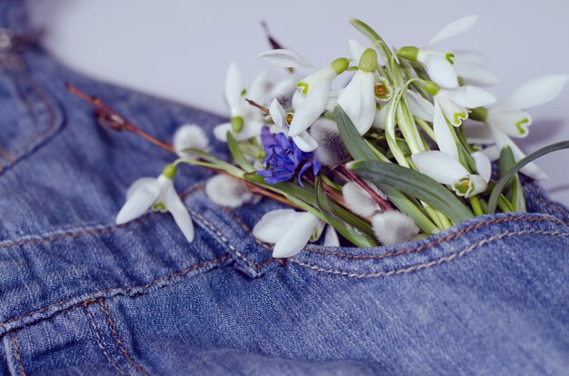 Photo snowdrop flowers bouquet in a jeans kids dress pocket.