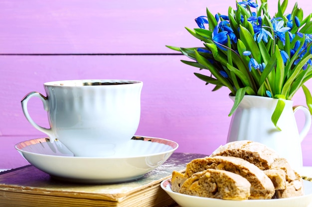 Snowdrops in a vase, a cup of tea and biscotti on the table