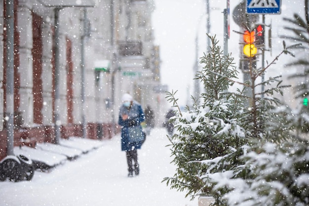 Снегопад на улицах города Размытая фигура женщины, идущей по заснеженной улице