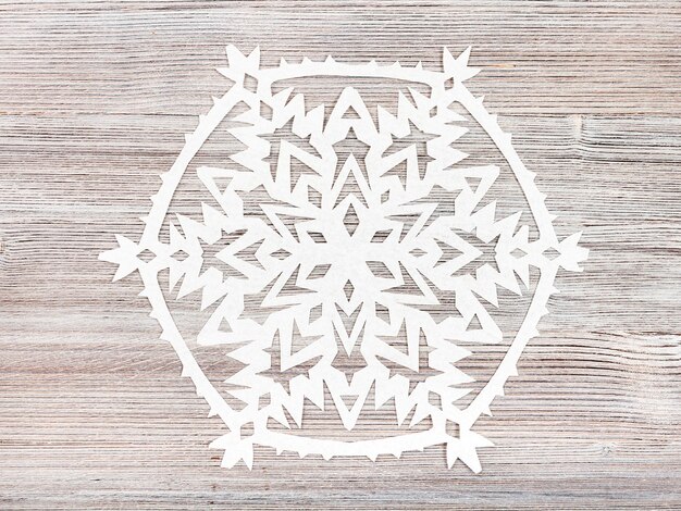 Photo snowflake cut out of paper on light brown board