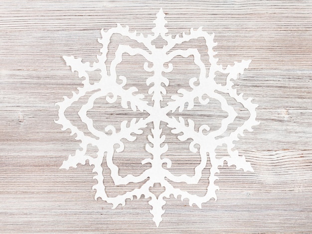 Snowflake cut out of paper on light brown surface