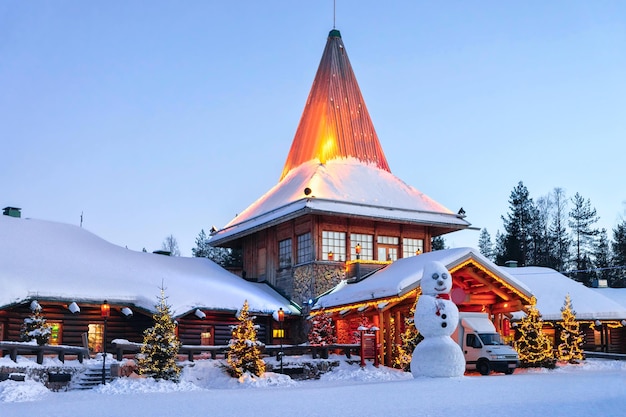 Photo snowman at santa office in santa claus village, rovaniemi, lapland, finland, on arctic circle in winter. in the evening